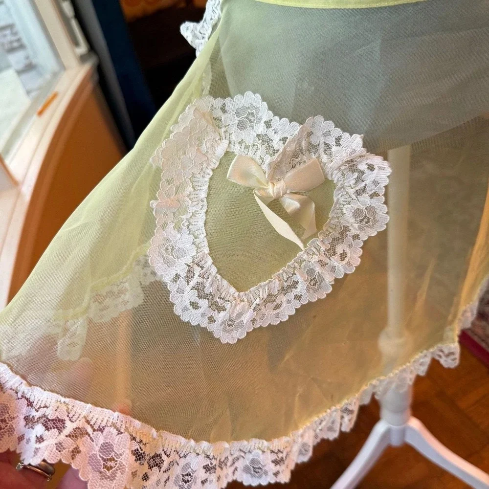 Vintage sheer yellow apron with ornate white lace trim and a bow-accented pocket